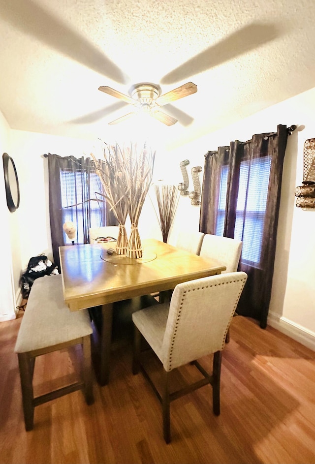 dining space with ceiling fan, hardwood / wood-style flooring, and a textured ceiling