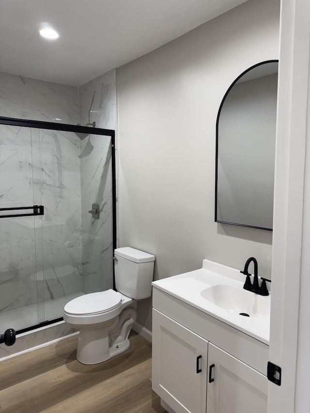 bathroom featuring hardwood / wood-style flooring, vanity, toilet, and walk in shower