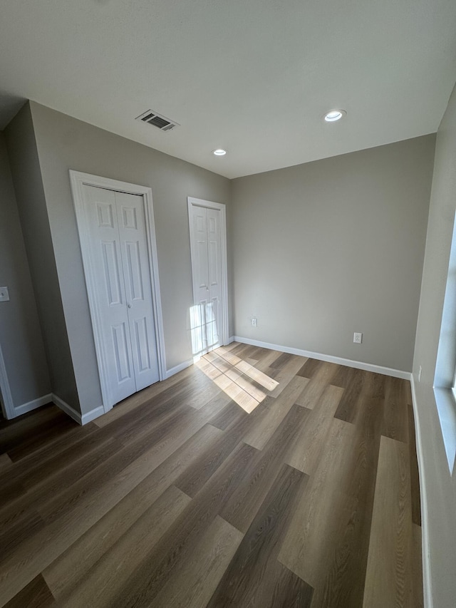 unfurnished bedroom featuring dark wood-type flooring and two closets