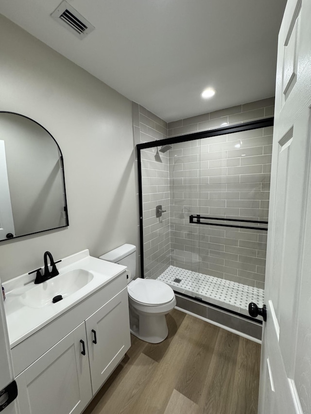 bathroom with hardwood / wood-style flooring, vanity, an enclosed shower, and toilet