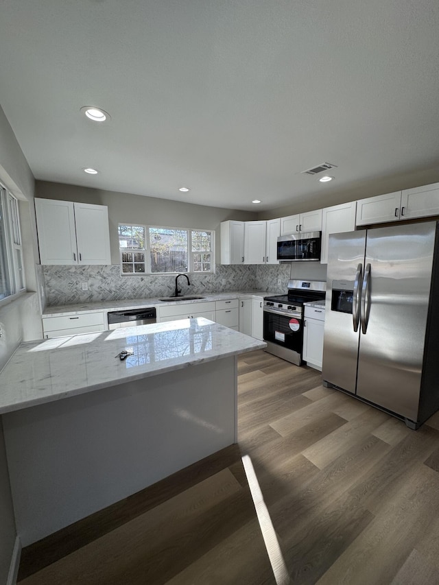 kitchen with light stone countertops, appliances with stainless steel finishes, sink, and white cabinets