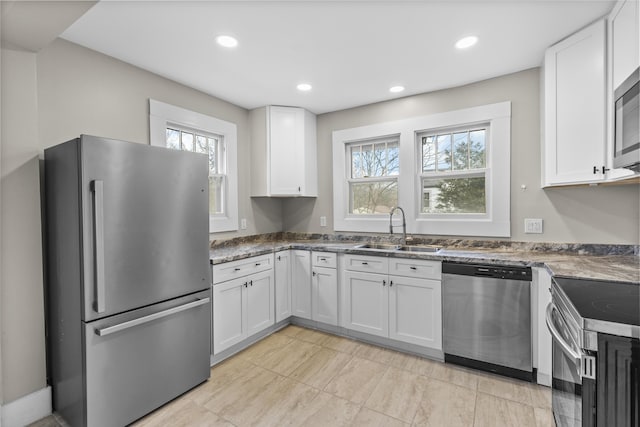 kitchen featuring appliances with stainless steel finishes, sink, a wealth of natural light, and white cabinets