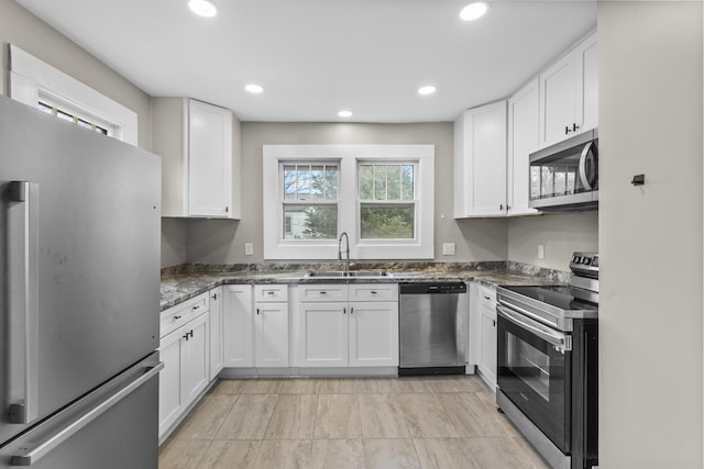 kitchen featuring stainless steel appliances, sink, dark stone countertops, and white cabinets