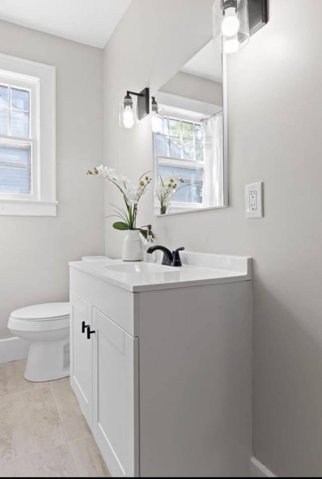 bathroom with vanity, a wealth of natural light, tile patterned floors, and toilet