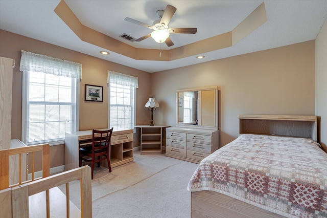 carpeted bedroom with a raised ceiling and ceiling fan