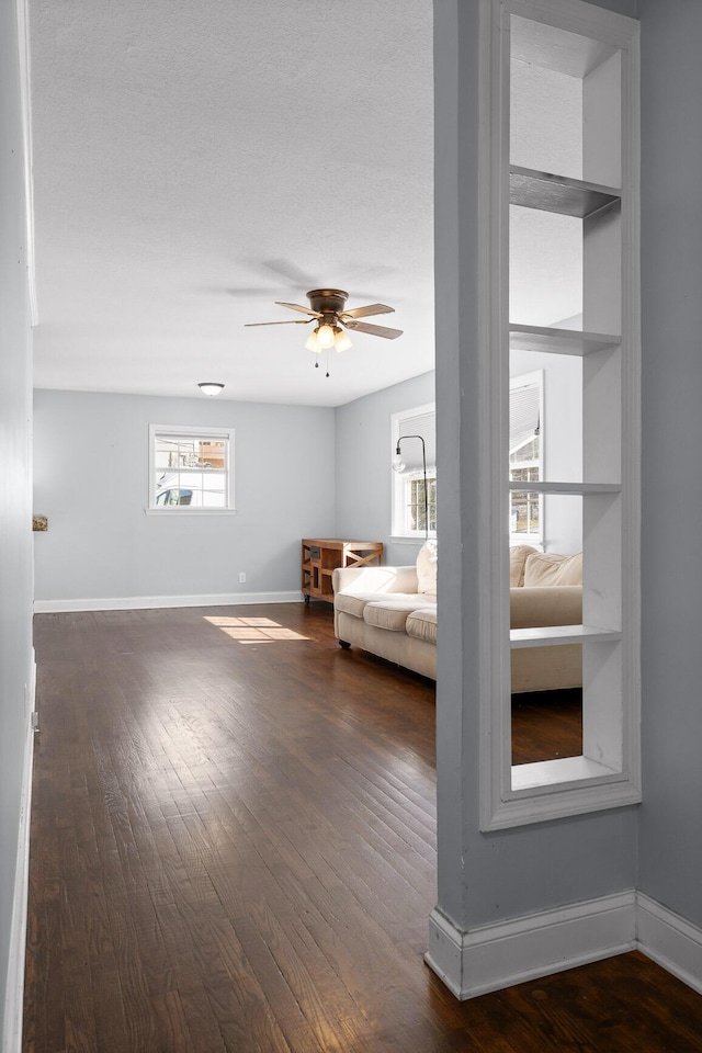 unfurnished room with dark wood-type flooring, built in features, and ceiling fan