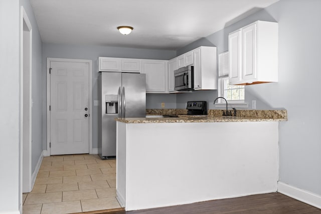 kitchen with sink, white cabinetry, light stone counters, kitchen peninsula, and stainless steel appliances