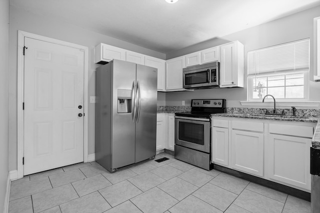 kitchen with white cabinetry, sink, light tile patterned floors, light stone counters, and stainless steel appliances