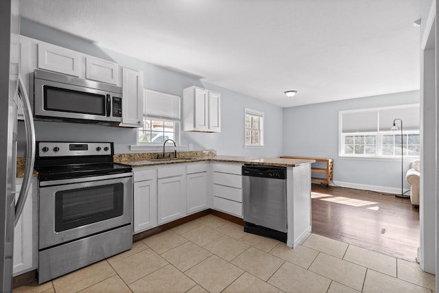 kitchen with appliances with stainless steel finishes, sink, white cabinets, and kitchen peninsula