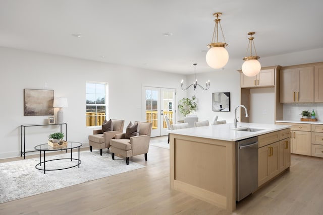 kitchen with sink, decorative light fixtures, light hardwood / wood-style flooring, dishwasher, and an island with sink