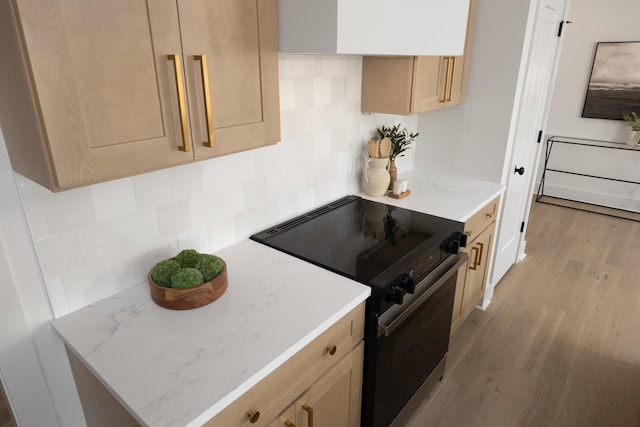 kitchen with light brown cabinetry, electric range, backsplash, and light hardwood / wood-style flooring