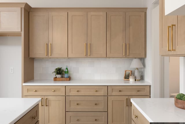 kitchen with decorative backsplash, light stone countertops, and light brown cabinets