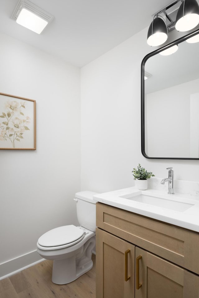 bathroom featuring vanity, wood-type flooring, and toilet