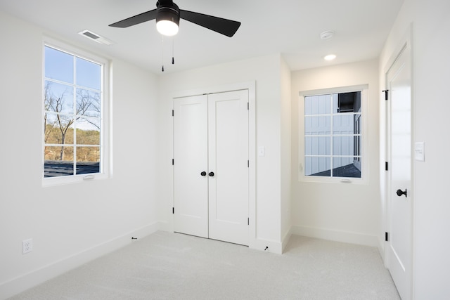 unfurnished bedroom with ceiling fan, light colored carpet, and a closet