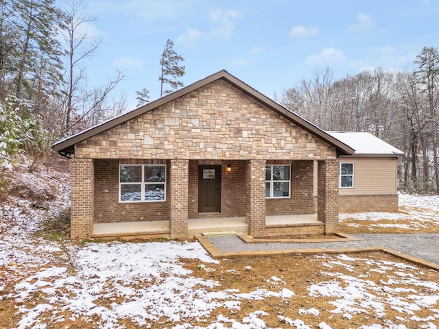 view of front of house featuring stone siding, brick siding, and covered porch