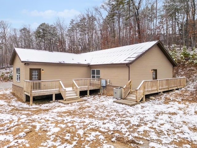 snow covered property featuring a deck and central AC