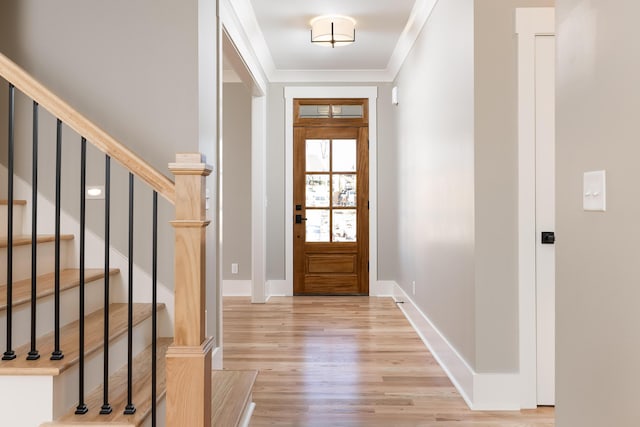 entrance foyer featuring light wood finished floors, baseboards, stairs, and ornamental molding