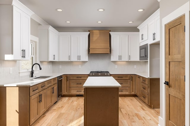 kitchen featuring built in microwave, a sink, light wood-style flooring, and custom exhaust hood