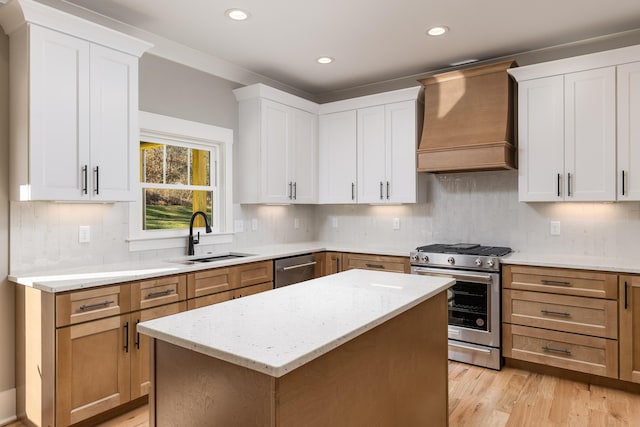 kitchen featuring appliances with stainless steel finishes, a sink, light stone countertops, light wood-type flooring, and premium range hood