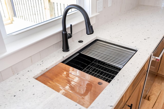 interior details with light stone countertops, brown cabinetry, and a sink