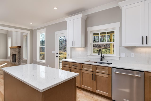 kitchen with light wood finished floors, decorative backsplash, stainless steel dishwasher, ornamental molding, and a sink