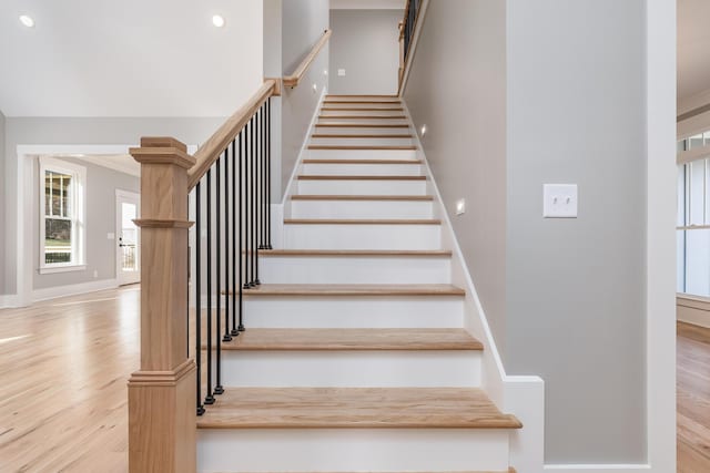 stairway featuring recessed lighting, wood finished floors, and baseboards