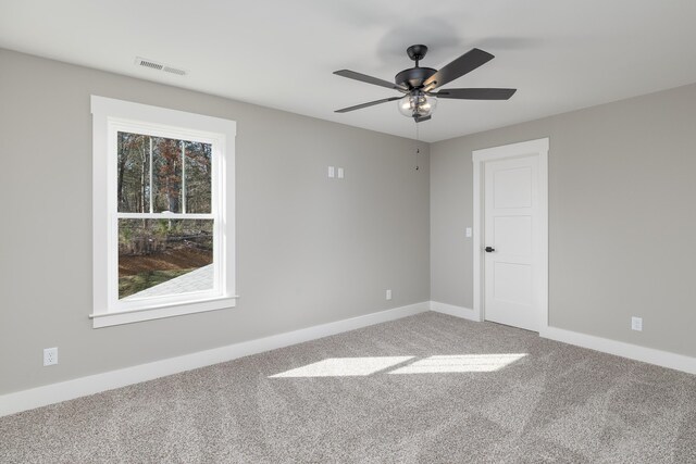 empty room featuring a ceiling fan, carpet, visible vents, and baseboards