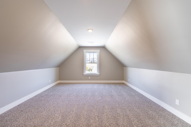 additional living space with light carpet, vaulted ceiling, and baseboards