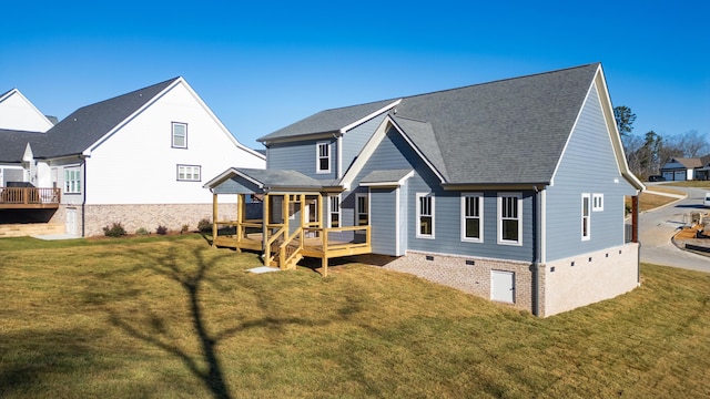 back of house featuring a shingled roof, a deck, and a yard