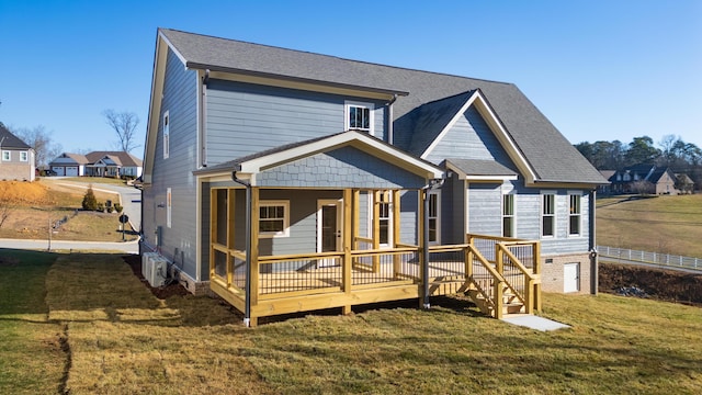 rear view of house with a lawn, a wooden deck, and a sunroom