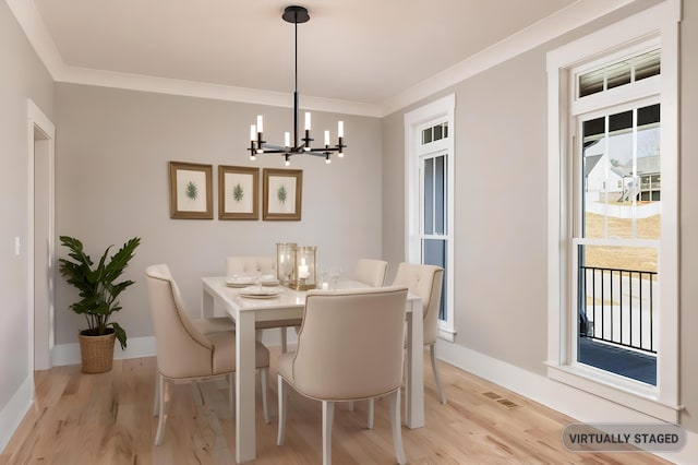 dining space with light wood-type flooring, an inviting chandelier, baseboards, and ornamental molding