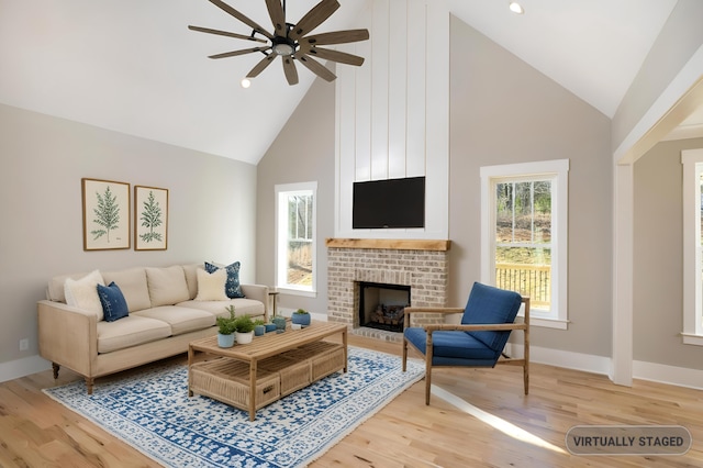 living area with baseboards, a fireplace, high vaulted ceiling, and wood finished floors