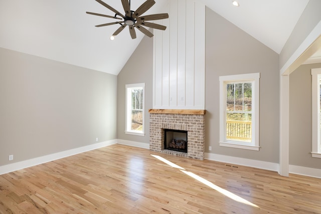 unfurnished living room featuring a brick fireplace, baseboards, and light wood finished floors