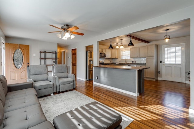 living room featuring beam ceiling, dark wood-type flooring, and ceiling fan