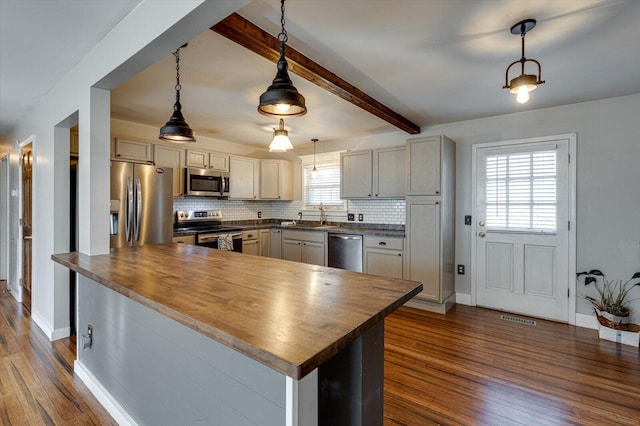 kitchen featuring hanging light fixtures, appliances with stainless steel finishes, and wood counters