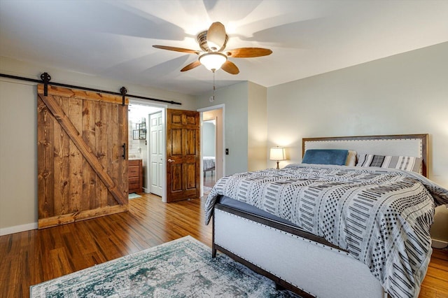 bedroom with ceiling fan, wood-type flooring, and a barn door