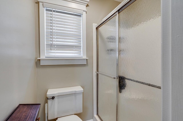 bathroom featuring toilet and a shower with shower door