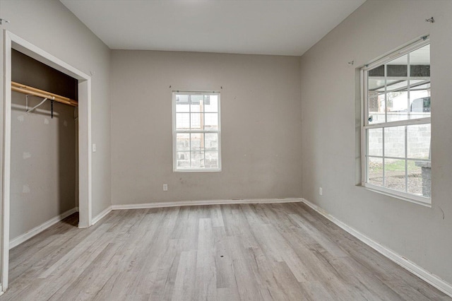 unfurnished bedroom with multiple windows, light hardwood / wood-style floors, and a closet