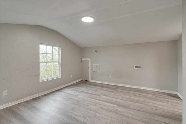 spare room featuring lofted ceiling and light hardwood / wood-style flooring