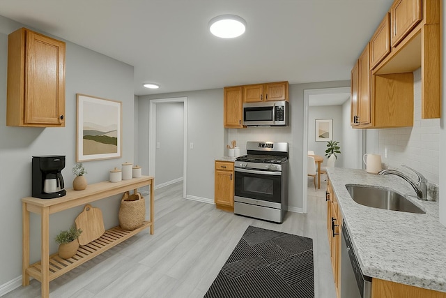 4807 14th Ave, Chattanooga, TN 37407 - kitchen with baseboards, decorative backsplash, a sink, light wood-style flooring, and appliances with stainless steel finishes