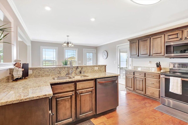 kitchen featuring pendant lighting, sink, crown molding, light hardwood / wood-style flooring, and stainless steel appliances