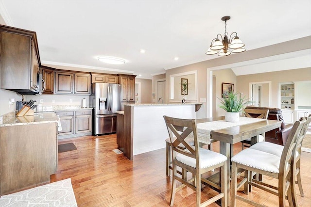 dining room with ornamental molding, a chandelier, light hardwood / wood-style floors, and built in features