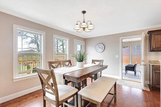 dining area featuring dark hardwood / wood-style flooring, ornamental molding, and a chandelier