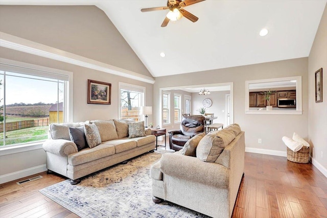 living room featuring ceiling fan with notable chandelier, wood-type flooring, and high vaulted ceiling