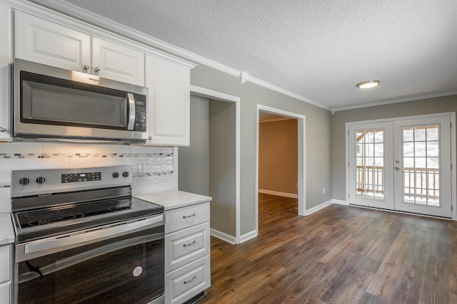 kitchen featuring tasteful backsplash, ornamental molding, stainless steel appliances, and white cabinets