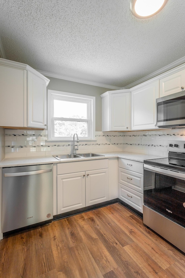 kitchen featuring sink, stainless steel appliances, white cabinets, and light wood-type flooring