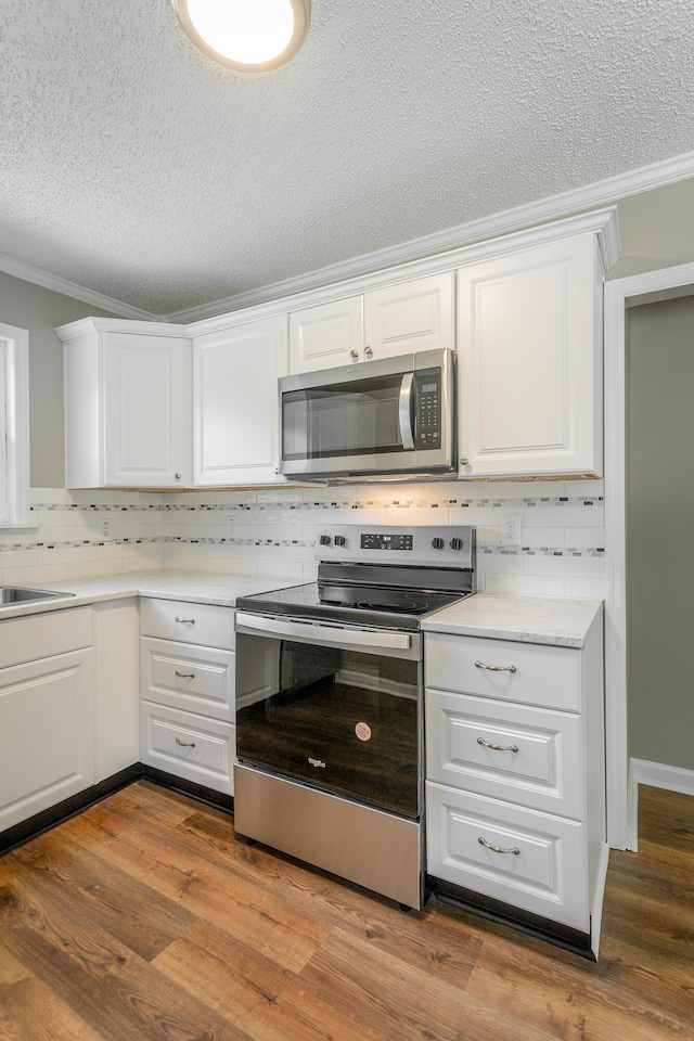 kitchen with white cabinetry, ornamental molding, and appliances with stainless steel finishes