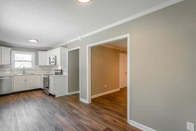 kitchen featuring appliances with stainless steel finishes, dark hardwood / wood-style floors, white cabinetry, sink, and ornamental molding