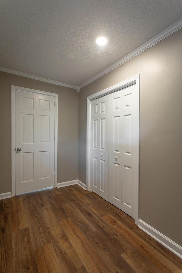 unfurnished bedroom with crown molding, a closet, dark hardwood / wood-style floors, and a textured ceiling