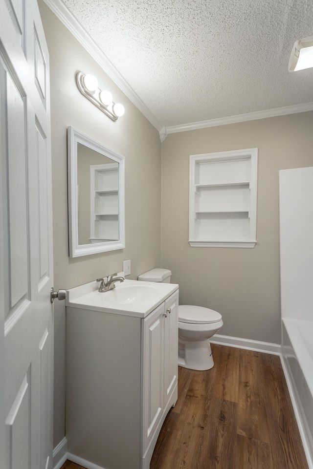 bathroom featuring built in features, vanity, wood-type flooring, ornamental molding, and a textured ceiling